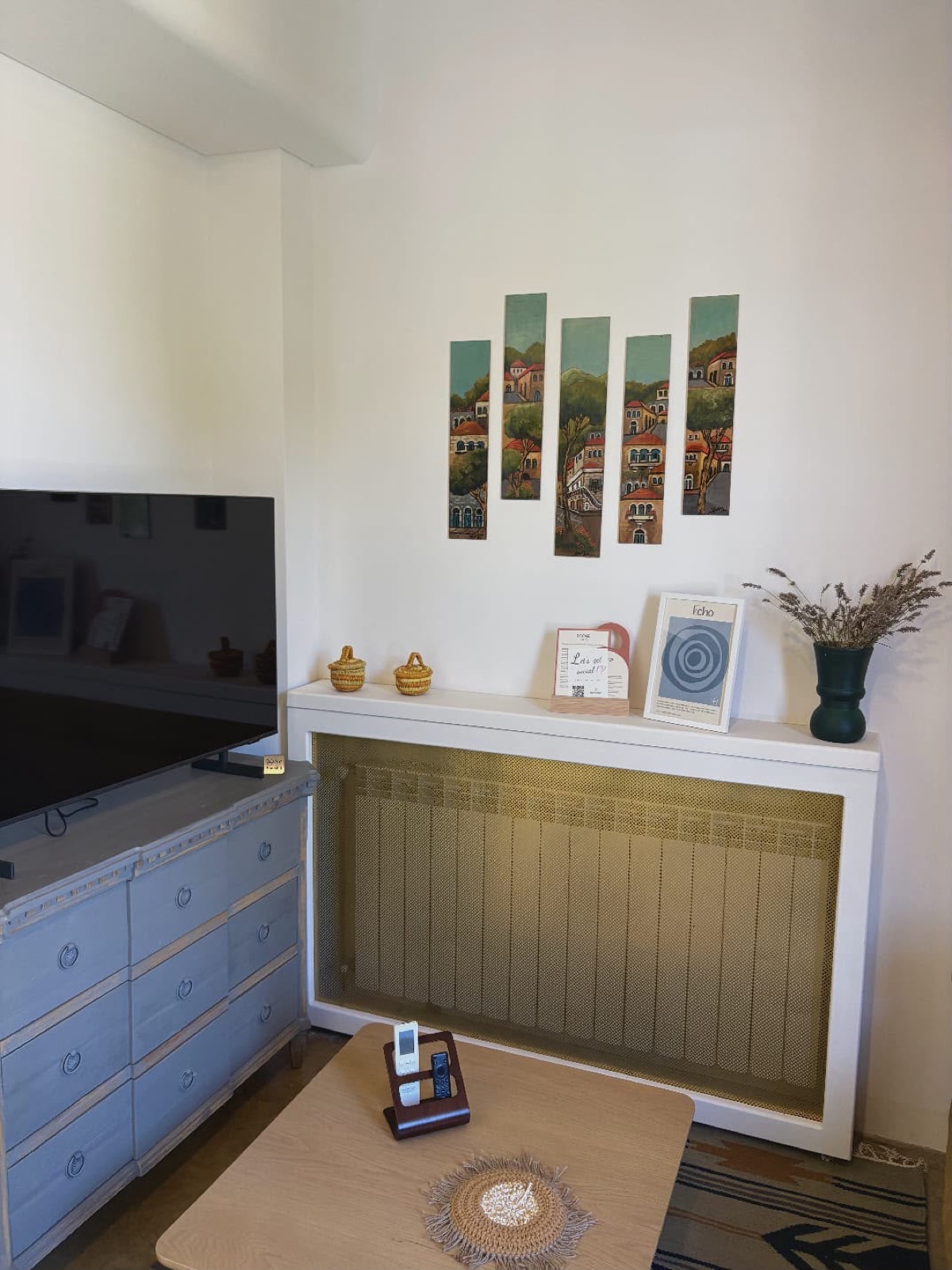 Echo room dresser and TV corner with paintings of Lebanese village houses
