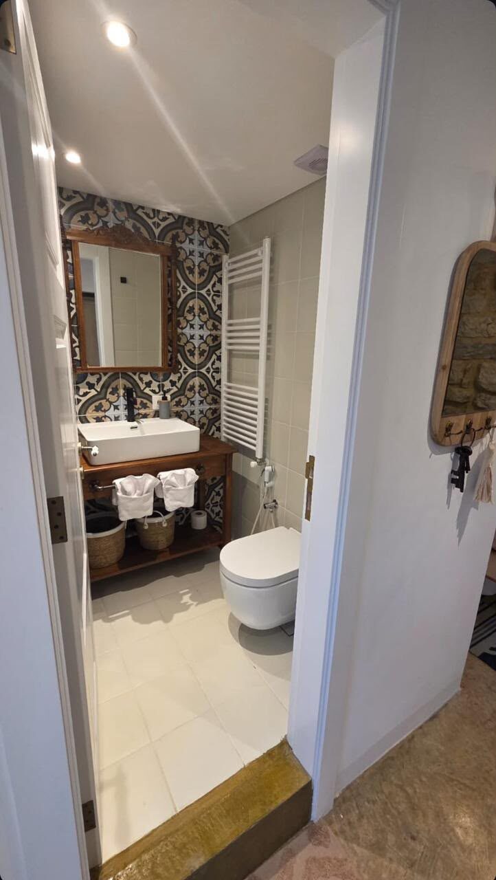 Echo en-suite bathroom with patterned tiles, a wood vanity and a modern toilet