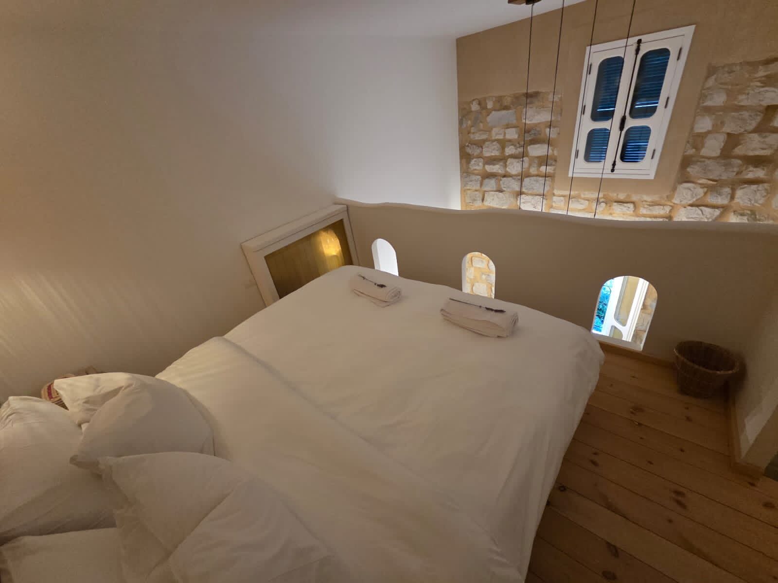 Echo bedroom with a made bed against the bare stone wall and a shuttered window