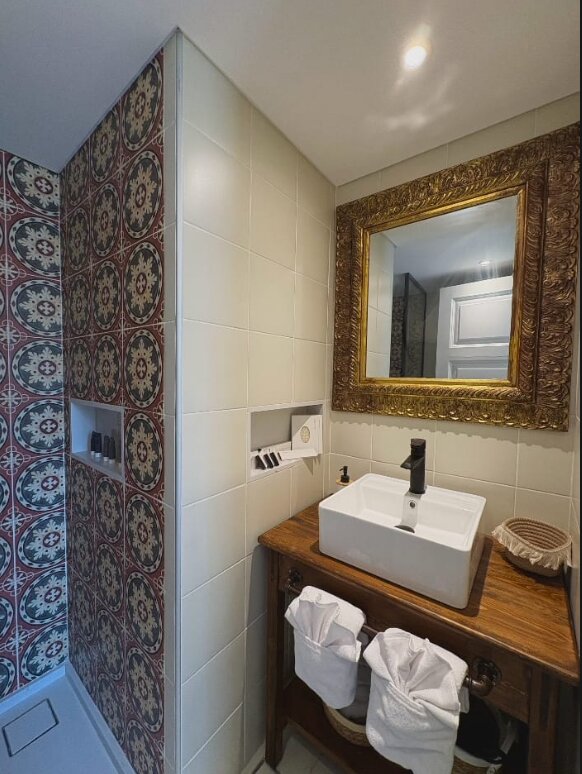 Whisper en-suite bathroom with red-and-blue patterned tiles, a gilt mirror and a vessel basin