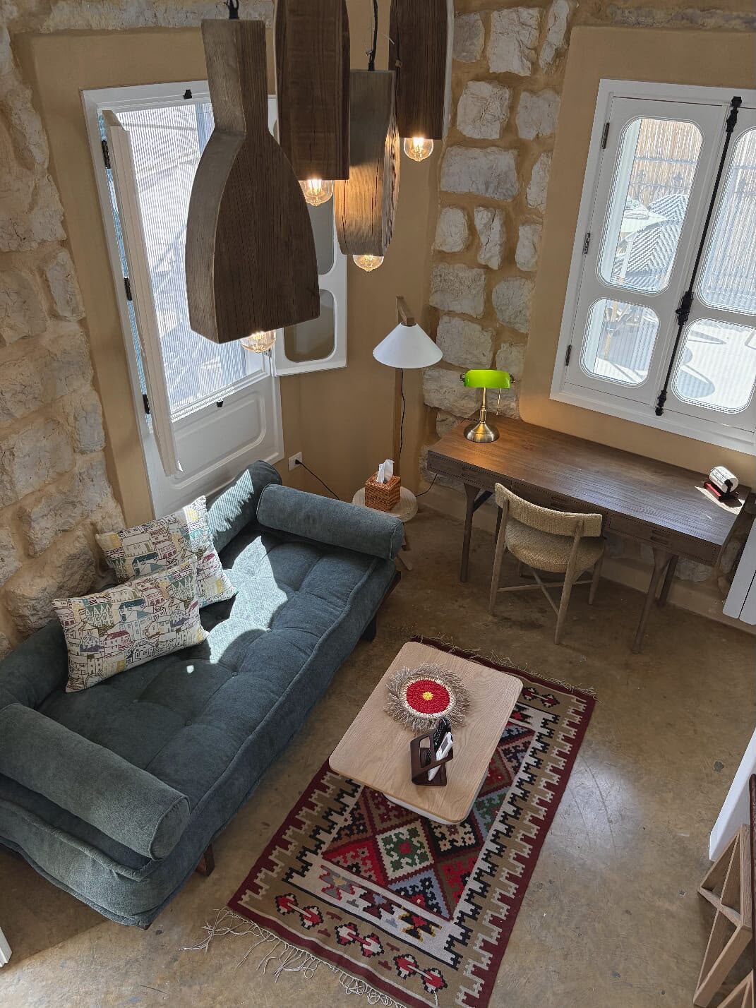 Whisper living corner with a green daybed and writing desk by the shuttered window over the souk
